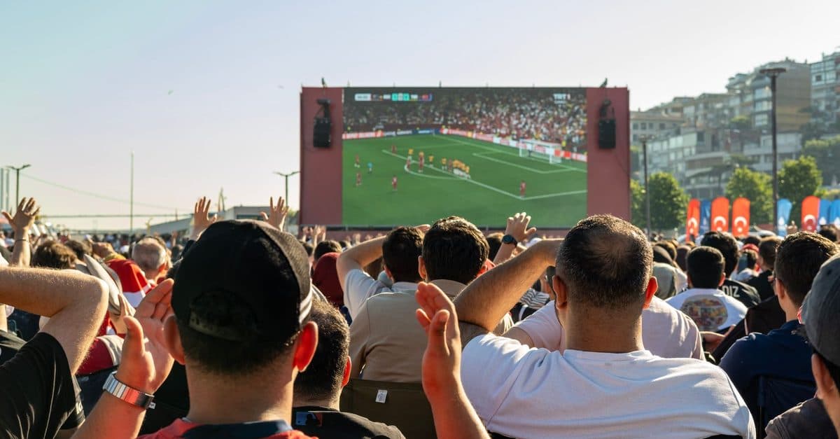 Tifozë duke ndjekur një ndeshje futbolli live në një ekran gjigant